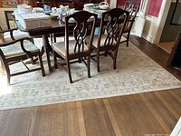 Area rug shown under dining table with chairs, showing overall pattern and condition.