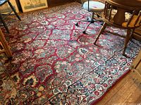 Overall view of red oriental wool rug with floral motif, showing general wear