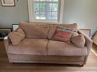Front view of the brown fabric sleeper sofa with three cushions and three throw pillows.