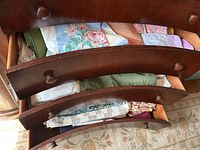 Drawers full of assorted table linens, visible floral and solid color tablecloths, placemats, napkins, and woven trivets.