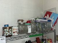Shelf showing assorted jars, tins, glass milk bottle, plastic pitcher, and food storage containers arranged together.