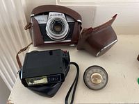 Front view of vintage Aires Penta 35 camera in brown leather case; Vivitar flash and Honeywell thermometer beside it