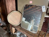 Rectangular mirror and octagonal frame side by side on wooden surface, visible chip on rectangular mirror edge