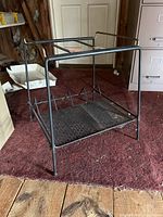 Front angled view of vintage metal TV and album stand on carpet, showing perforated base and vertical dividers for album storage.