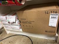 Photo showing one large cardboard case labeled McKesson Vinyl Exam Gloves Powder-Free, 10 boxes per case, medium size, 100 gloves per box.