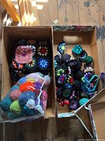 Box with assorted crocheted wool pieces and granny squares with floral designs in colorful yarn