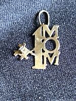 Close-up of the 14K gold #1 MOM pendant with visible diamond accent, showing front detail and bail loop.
