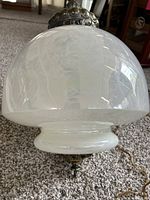 Close-up of the lamp's iridescent pearl carnival glass dome shade placed on carpet.