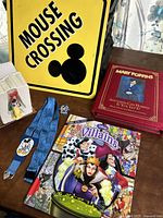 Photo showing the entire lot including the yellow Mouse Crossing metal sign, key strap, Villains book, Mary Poppins books, and pin