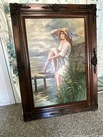 Full view of the oil painting showing a lady on a dock with a dark ornate wood frame.