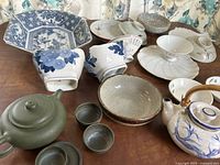 Wide view of various hand-painted and handcrafted ceramic dishes, bowls, and tea pots on table