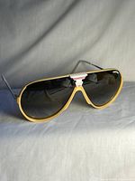 Front view of sunglasses showing yellow frame, amber lenses, white top accent