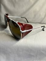 Angled front view showing white frame, red leather blinders, brown lenses and Carrera branding on temple.