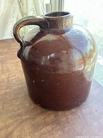 Brown glazed vintage stoneware jug showing handle and round body.