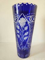 Front view of very tall cobalt blue crystal vase with floral cut to clear design and scalloped rim