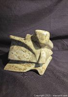 Angled view of abstract soapstone sculpture on black cloth background