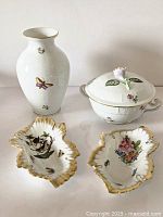 Four pieces displayed on white surface: vase at rear left, covered dish at rear right, two leaf dishes front.