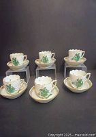 Six teacups and six saucers arranged on risers against black background