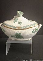 Front view of the oval porcelain dish with decorative floral decals and gold trim, lid topped with single sculpted rose handle and side rose handles