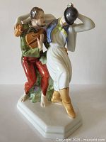 Front view of figurine showing musician playing lute and unsteady companion