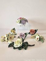 Front view of porcelain flower collection showing various large realistic flowers including roses and orchids arranged on white background