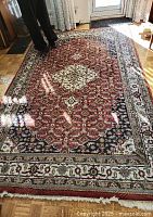 Full view of rug on parquet floor showing overall pattern and color scheme