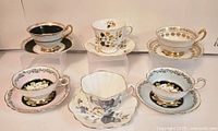 Six teacup and saucer sets arranged in two rows of three on stands