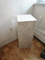 Full-height view of white marble plinth showing natural veining and proportions