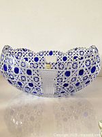 Side view showing deep oval shape, scalloped edges, and cobalt blue geometric overlay cut to clear sections.