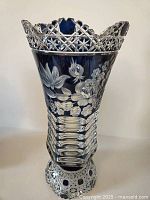 Front view of teal over clear cut glass vase showing floral etching and geometric cuts