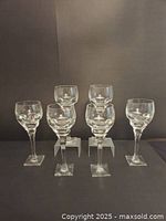 Six Moser crystal wine glasses arranged in two rows against a gray backdrop.