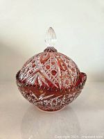 Side angle front showing intricate cut patterns on the red Bohemian style lead crystal candy dish with lid and clear faceted knob.