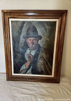 Frontal view of framed oil painting of an elderly man smoking a pipe, showing details of the figure, hat, and pipe.