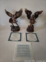 Both sculptures, two certificates of authenticity, and collection preview sheet arranged on white surface