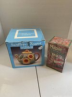 Retail box for sunflower teapot beside sealed Maple Herbal tea box