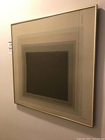 Frontal view of the framed abstract artwork showing concentric squares and gold-tone frame