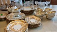 Multiple stacks of Aynsley bone china plates, bowls and cups on table