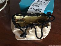 Opera glasses in beige satin drawstring pouch with blue box in background.