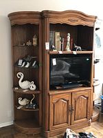 Three-piece wooden cabinet set with TV storage and open shelves, medium brown finish, curved top edges, decorative carved trim.