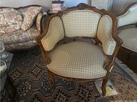 Front view showing the upholstered seat, backrest, and arm padding framed in carved wood.