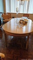 Full view of oval extendable dining table with two leaves and decorative items on top