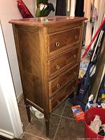 Wood dresser angled front showing four drawers with ring pull handles and carved edges, medium brown wood finish.