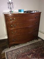 Front view of the wood dresser showing four curved drawers with metal handles and decorative legs.