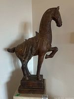 Front left side view of the horse figurine on a pedestal