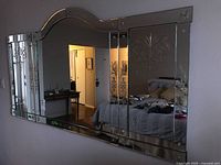 Overall view of full mirror assembly mounted on wall showing arched top and decorative etched floral patterns