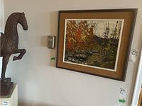 Overall view of framed painting mounted on wall next to decorative horse sculpture