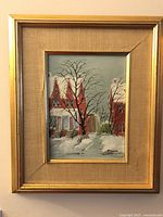Framed painting of red brick houses in snow with bare trees, signed McGroch lower right