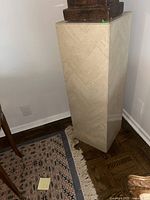 Full view of stone clad pedestal showing the herringbone stone tile pattern and the rectangular shape.