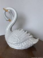 Front-side view of the white ceramic swan planter showing intertwined necks and detailed feathers with gold-tipped beaks.