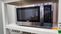 Front view of RCA microwave oven showing its silver body, black window on the door, and the digital control keypad on right side.